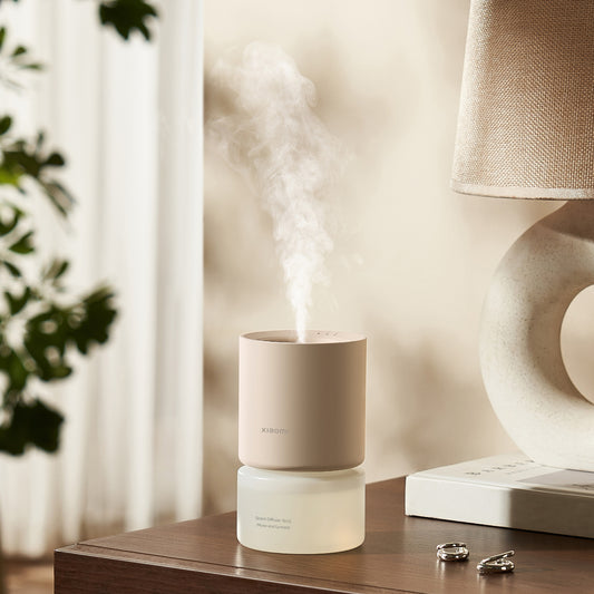 Diffuser emitting mist on a table with a lamp and plant in the background