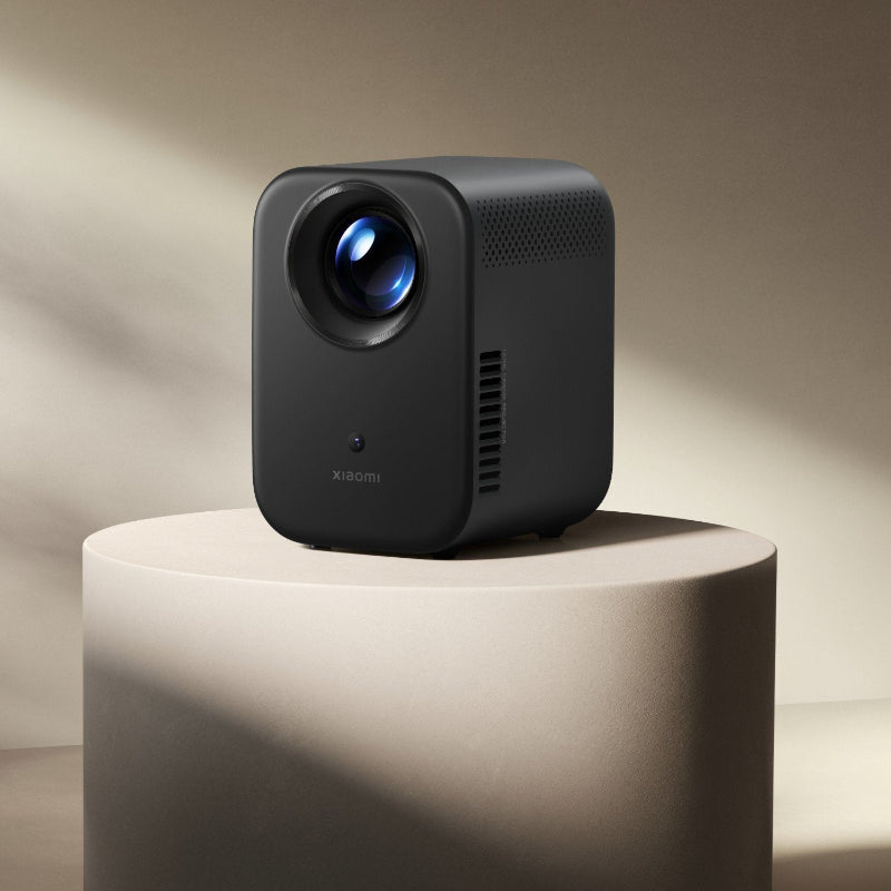 Black Xiaomi projector on a beige pedestal with a neutral background