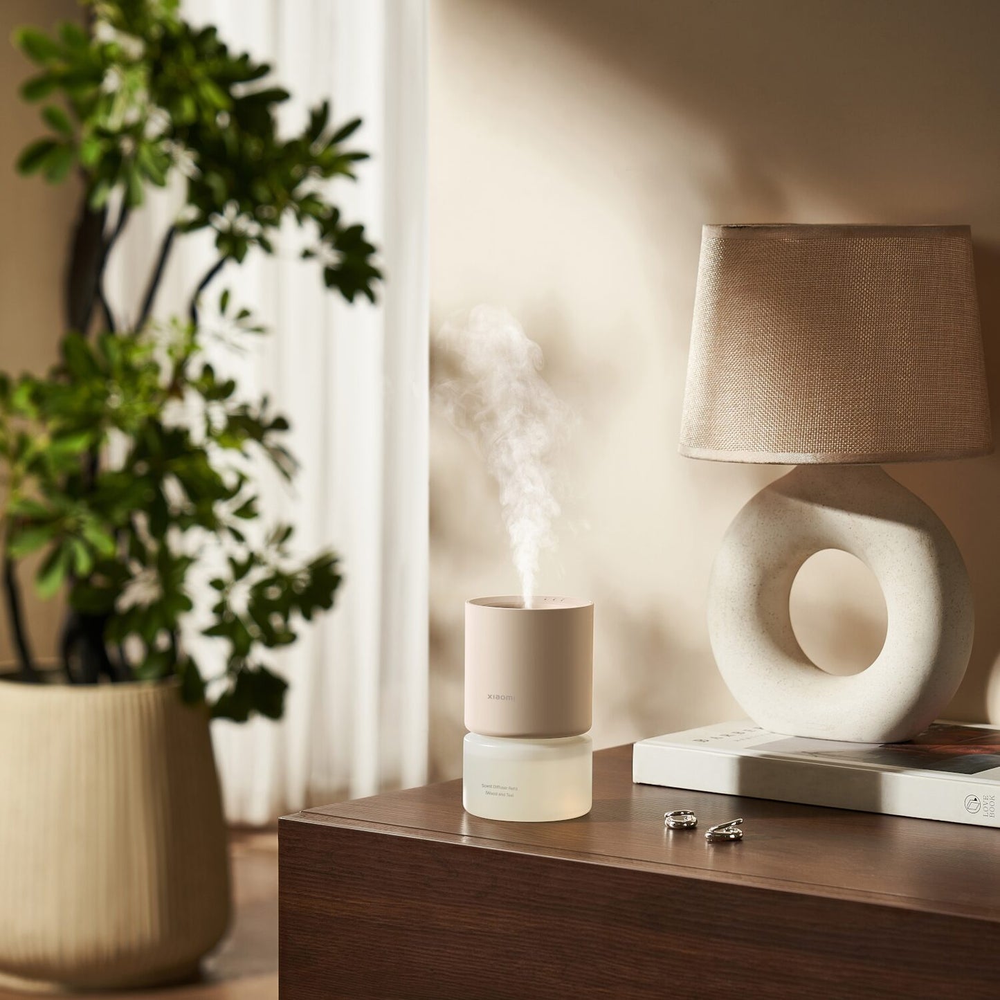 Xiaomi Smart Scent Diffuser on a wooden surface with a lamp and plant in the background