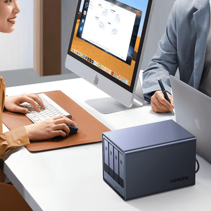 Two people working at a desk with a UGREEN external hard drive in the foreground.