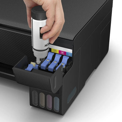 Hand inserting a ink cartridge into a printer with visible ink colors.
