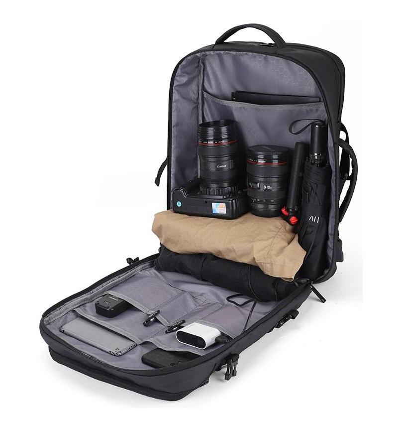Open black adjustable laptop backpack showing organized interior compartments with camera gear, clothing, tablet, and accessories neatly stored.