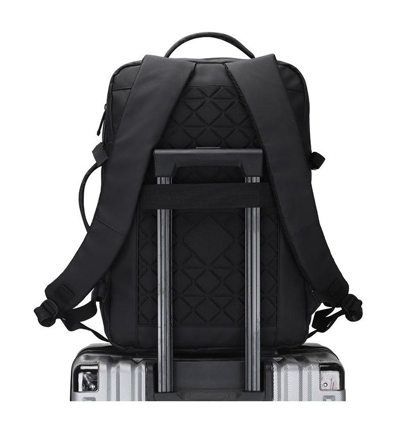 Black adjustable laptop backpack attached to suitcase handle using built-in luggage strap, showing travel-friendly design and padded back support