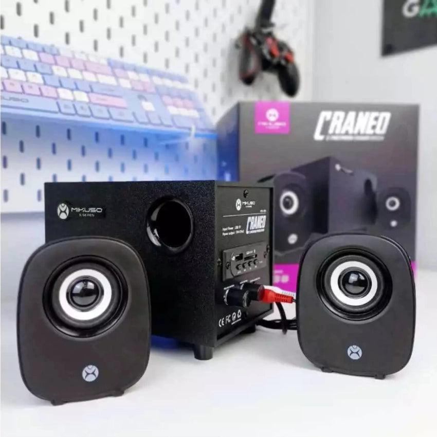 Pair of black Mikuso XS-38 speakers with visible branding on a white surface, with a blurred background.
