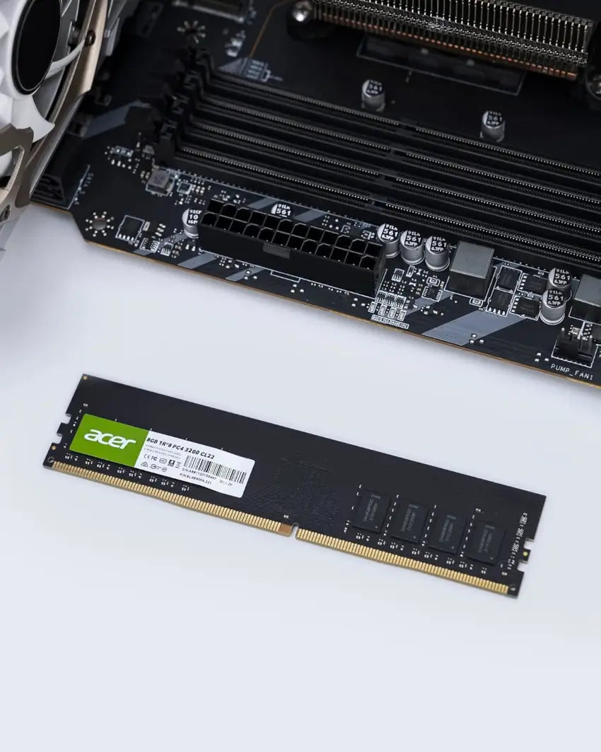 Acer RAM module on a white surface with a computer motherboard in the background