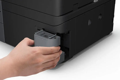Person inserting a printer waste cartridge into a black printer on a white surface