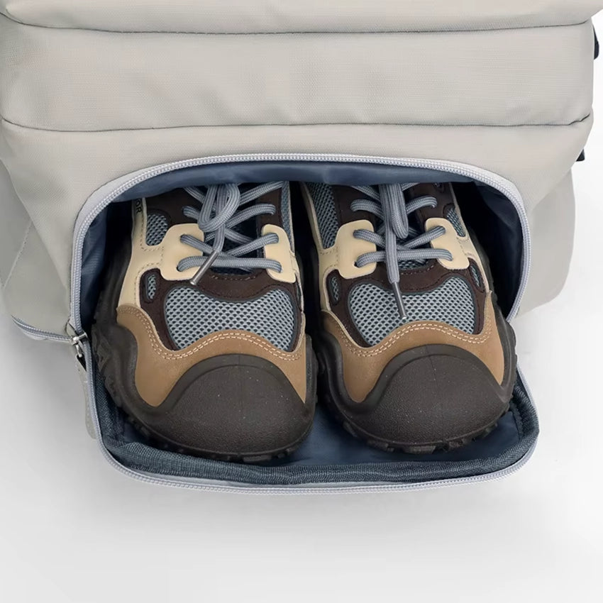 Pair of brown and black shoes inside the M-Link 15.6" Multi-compartment backpack with padded straps and handles in beige