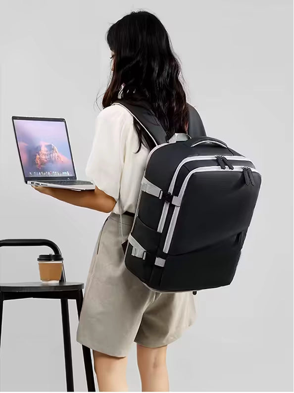 Person holding a laptop with a black backpack on a plain background