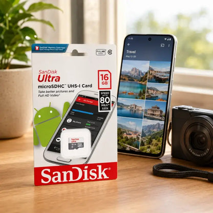 SanDisk Ultra 16GB microSDHC UHS-I Card in its retail packaging, displayed on a wooden table next to a smartphone and a camera.